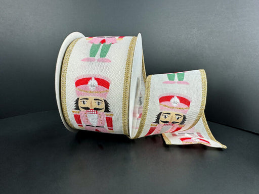 The 2.5X10Y Pink-Green Cutesy Nutcrackers Ribbon (76527-40-26) features a playful nutcracker soldier in a red uniform with gold trim, accented by pink and green on a black background.