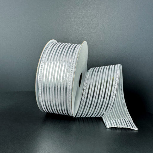 A spool of 1.5X10Y White Satin/Silver Metallic Embossed Vertical Grain Ribbon (76555-09-51) stands upright against a dark background, with a length unrolled and elegantly draped beside it.