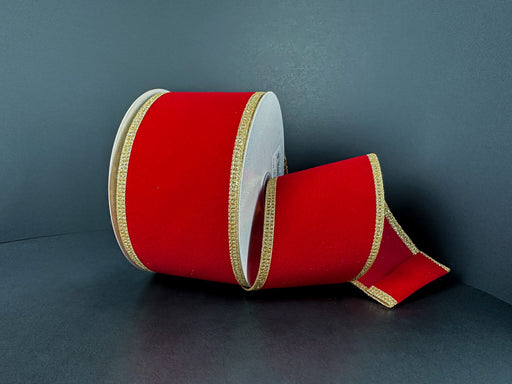 A 2.5x10Y Red Velvet/Gold Glitter Edge Ribbon (76561-40-15) is partially unspooled, resting on a dark surface against a plain dark background.