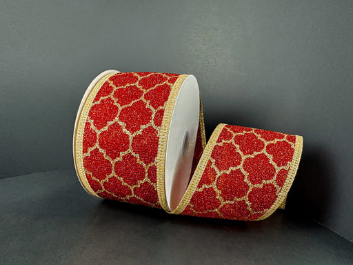 The 2.5X10Y Red Fuzzy Metallic/Gold Quatrefoil Ribbon (76574-40-15) features a glittery gold quatrefoil pattern and gold edges on red, elegantly displayed partially unrolled against a dark background.