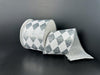 A 2.5X10Y Silver Metallic/White Harlequin Ribbon (78513-40-51) with a silver and white diamond checkered pattern is unrolled on a dark surface, set against a dark background.