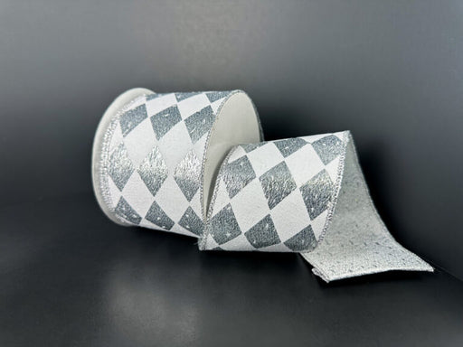A 2.5X10Y Silver Metallic/White Harlequin Ribbon (78513-40-51) with a silver and white diamond checkered pattern is unrolled on a dark surface, set against a dark background.