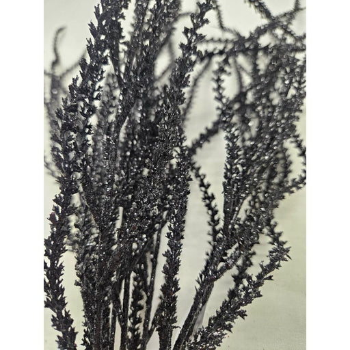 Close-up of several 22 Black Willow with Glittered 82841-BK branches standing upright against a light background, showcasing their textured surfaces and sparkling glitter details.