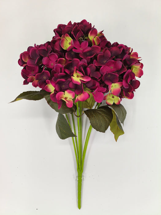 The 20" Burgundy Hydrangea Bush with 7 Stems 85434-BG showcases dark magenta and yellow-green hydrangea flowers with green leaves, displayed against a plain white background.