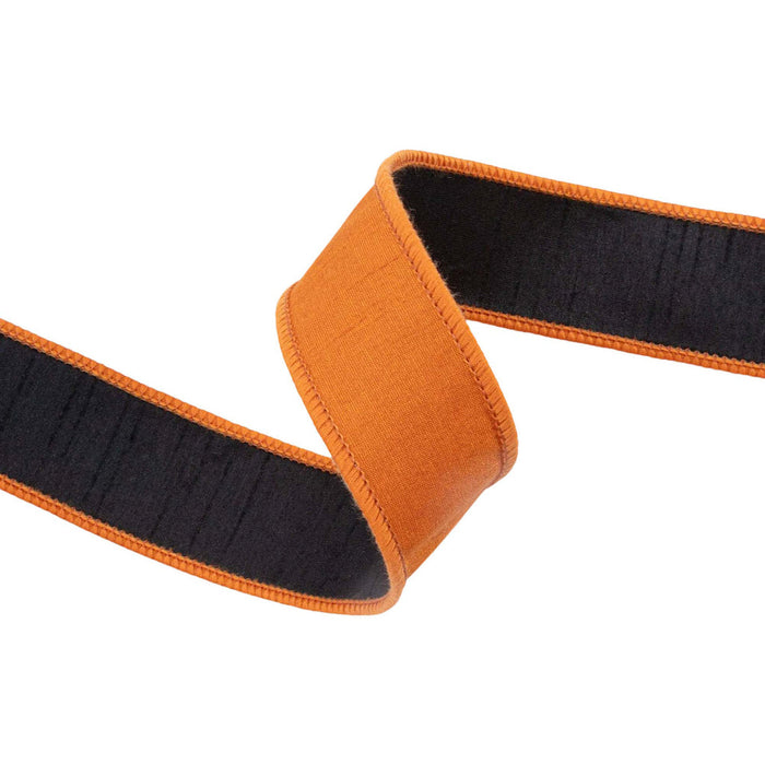 A close-up of the 1.5″ Designer Orange Double-Fused Dupioni Wired Ribbon (9105W-030-38E), featuring vibrant orange with black striping, twisted into a loose knot against a white background—ideal for autumn wreaths or Halloween decorating.