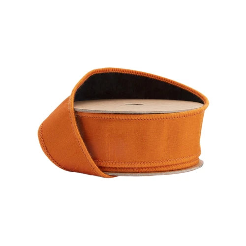 A spool of 1.5″ Designer Orange Double-Fused Dupioni Wired Ribbon (9105W-030-38E), partially unrolled and encircling a cardboard cylinder—perfect for adding a luxurious touch to autumn wreaths or Halloween décor.