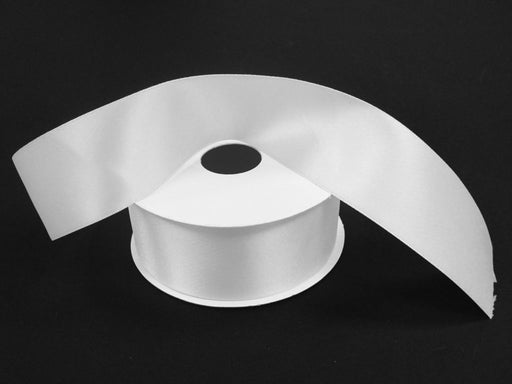 A spool of 1.5 by 25 yards white unwired double-faced satin ribbon, product code 981409-01, with one end elegantly draped over, set against a black background.