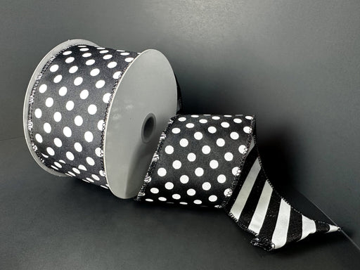 A 2.5 x 10 yd double-sided ribbon spool (D73582-40-20) in black satin with large white dots on one side and black-white glitter candy cane stripes on the other is partially unrolled against a plain black background.
