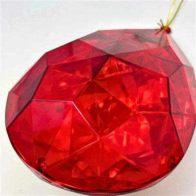 A close-up of the 6.3" x 4" x 9" Red Plastic Drop Ornament (DCORN5408RD), shaped like a gemstone, faceted and translucent, hanging by a gold string against a plain white background.