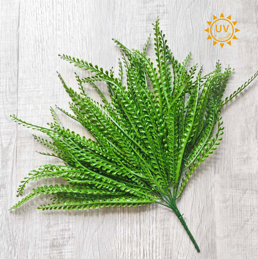 The Green Bead Grass Bush – Plastic Leaves – 7 Stems – 16 Inches (E66251557) is displayed on a light wood surface with a UV Protected sun icon, ideal as greenery filler or for wreath making projects.