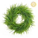 The 24" Two Tone Green Bead Grass Wreath (E66261813), made of artificial foliage with small leaves, is shown on a white background. A sun icon in the top-right highlights its UV protection.