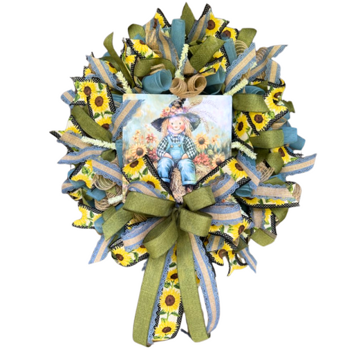 The Fall Denim Scarecrow Completed Wreath features sunflower-patterned ribbons, bows, and a central sign with a cheerful scarecrow, sunflowers, and a blue sky. Shipping is included.