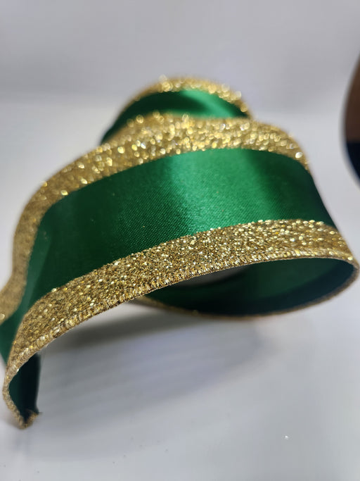 A close-up of the 2.5X10YD Emerald Gold Vertical Glitter Stripe Ribbon (LS31207R), featuring glittery gold edges, curled on a white surface.