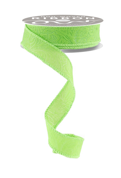 The 1X10YD Lime Green Floral/Leaves Ribbon, product number NR100030, is unwinding to reveal its intricate floral and leaves pattern, with the wired ribbon spiraling downward to display its decorative edge.