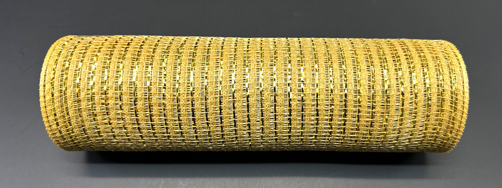 The 10X10Y Gold Breeze Metallic Mesh XB240810-15 roll is shown on a flat, dark gray surface in a top-down view.
