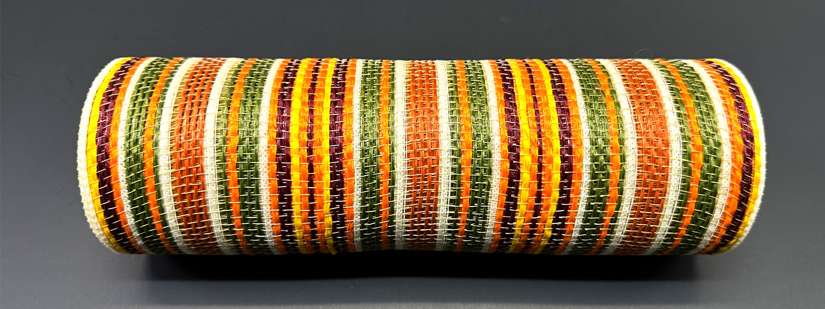 The 10X10Y Orange-Moss-Brown-Ivory Striation Mesh (XB240910-19) is a cylindrical woven item with colorful vertical and horizontal stripes, shown on a dark gray background.