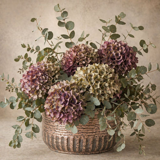 Amethyst hydrangea 10 inch metal sign with purple and beige hydrangeas, eucalyptus stems and textured bronze pot against a warm neutral background, TTE-687.