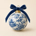 Blue chinoiserie 10 inch metal Christmas sign with porcelain-style ornament featuring blue and white floral and pagoda pattern, navy velvet bow, gold cap and beige background, TTE-668.