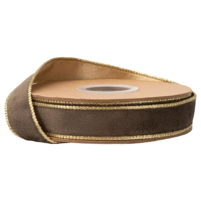 A spool of Reversible Brown Velvet Wired Ribbon with Gold Shimmer Satin Back (1 Inch x 10 Yards, 7115W-850-25E) is partially unrolled and resting on a white surface. This ribbon features a luxurious brown velvet side with shiny gold trim and a shimmering gold satin reverse for added elegance.
