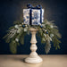 Blue and white chinoiserie Christmas gift box with navy velvet bow, frosted greenery, and eucalyptus arranged on a white candlestick