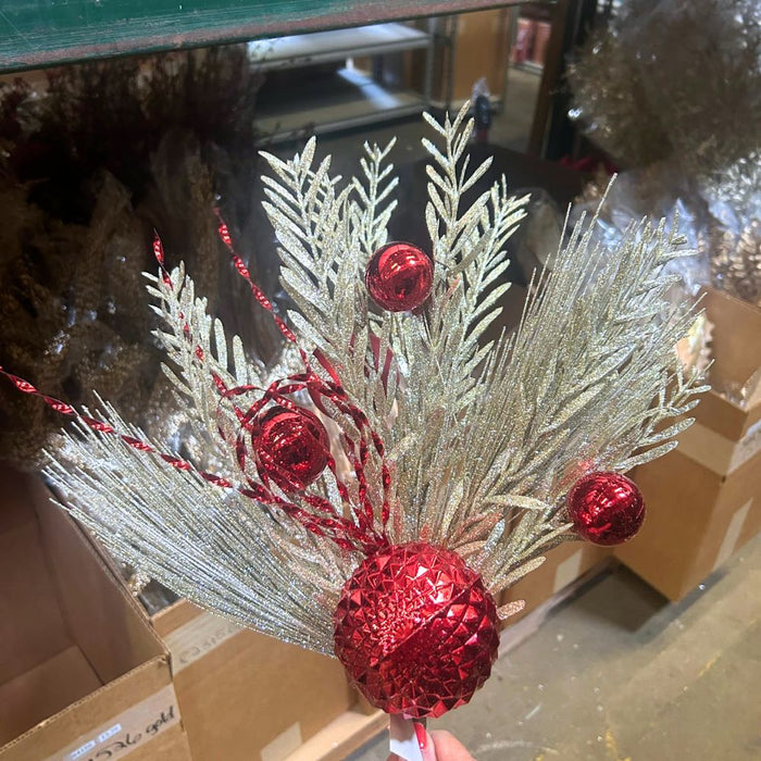 The 24" Red Needle Pine Plastic Leaf Spray 85154-RD features glittery silver pine branches, shiny red ornaments, and textured baubles—all arranged on a plain white background for a festive Christmas display.