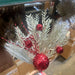 The 24" Red Needle Pine Plastic Leaf Spray 85154-RD features glittery silver pine branches, shiny red ornaments, and textured baubles—all arranged on a plain white background for a festive Christmas display.