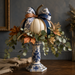 Fall metal sign featuring a white pumpkin with navy and blue floral ribbon, eucalyptus and autumn leaves displayed on a blue and white chinoiserie candlestick.