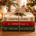 Christmas book stack metal sign with red green and cream books tied with twine, greenery and red berries