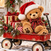 Christmas teddy bear wearing a red Santa hat and plaid bow, sitting in a rustic red wagon filled with wrapped presents, evergreen greenery, pinecones, and red berries. Flat metal wreath sign TTE-868.