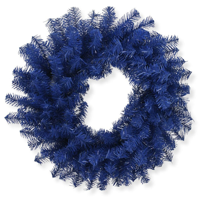 A 24" Royal Blue Artificial Pine Wreath 82295-BL, made with dark blue artificial pine branches in a classic circular form with a hollow center, is displayed against a white background.