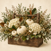 Fall toolbox arrangement sign featuring cream hydrangeas, white pumpkins, berries, magnolia leaves, eucalyptus, and seasonal greenery in a wooden toolbox.