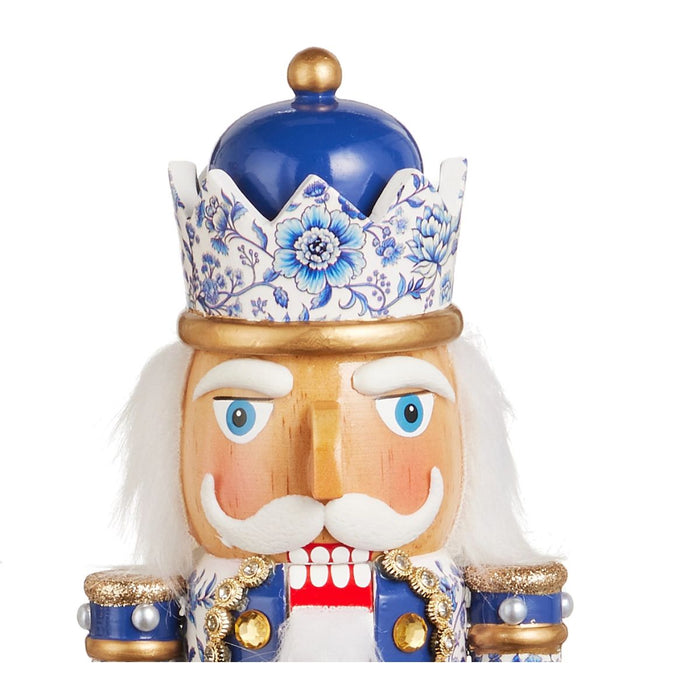 Elevate your blue and white Christmas decor with the 14.75″ Chinoiserie Nutcracker Christmas Figure (RAZ 4623009), featuring intricate blue, white, and gold chinoiserie patterns, gold details, a blue hat, and a classic white beard—all set atop a gleaming gold base for the perfect festive accent.
