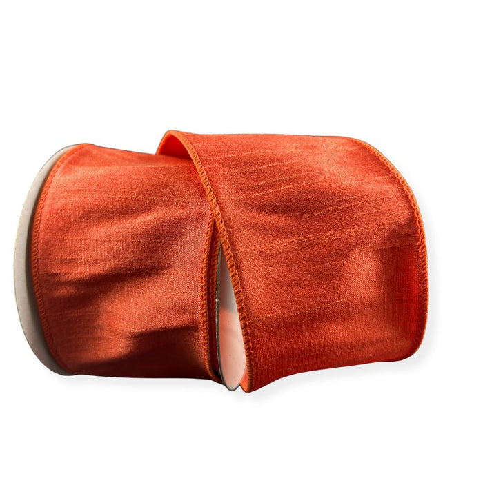 A partially unrolled roll of 2.5" Orange Faux Dupioni Wired Ribbon (72434-40-19) with a subtle sheen, set against a white background—perfect as wired ribbon for wreath making supplies or creative decor projects.