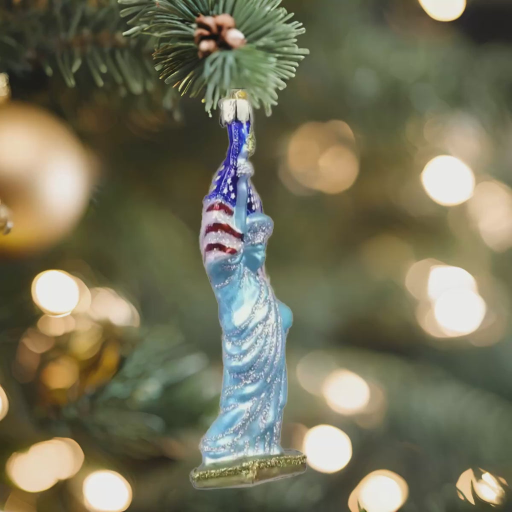 The Statue of Liberty Merck Family Old World Christmas 10181 is a glittery, hand-painted glass ornament with an American flag and gold base—ideal for adding festive, classic charm to your Christmas tree.