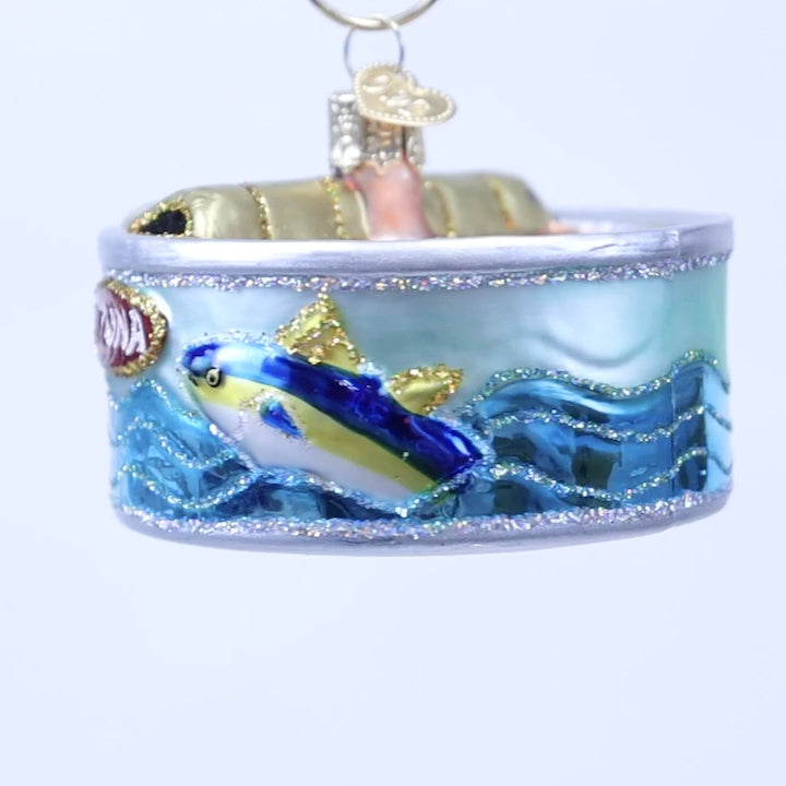 Add protein-packed whimsy to your tree with the Canned Tuna Old World Christmas Ornament 32616—a charming ornament shaped like a tuna can. It features a blue fish and waves on the label, a partially opened lid revealing pink “tuna” inside, and a gold pull tab adorned with a heart charm.