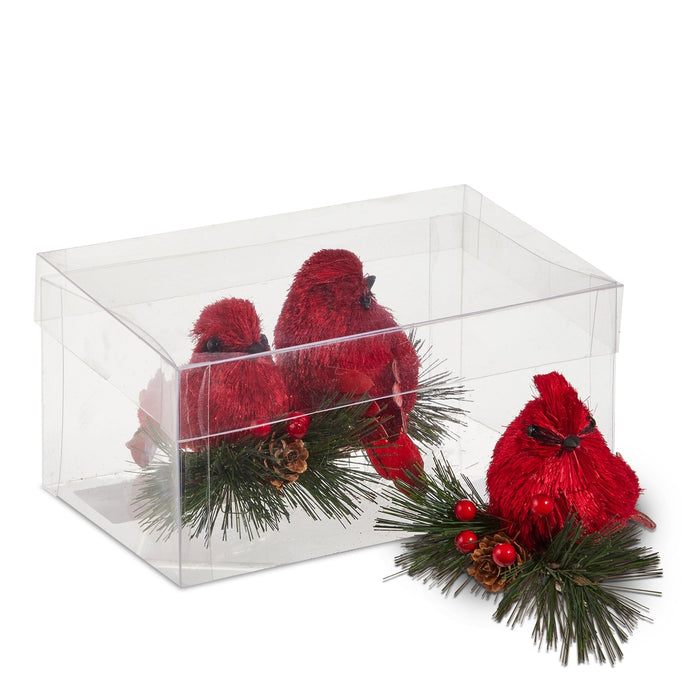 Set of 3 Cardinal on Greenery Ornaments by RAZ Imports (item 4554022), featuring vibrant red cardinals perched among pine needles, berries, and pinecones—beautifully displayed inside and beside a clear plastic box, making them the perfect Christmas tree decorations.