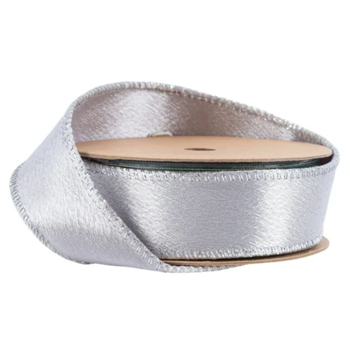 A spool of Silver Shimmer Satin Wired Ribbon with Silver Backing (1 Inch x 10 Yards | 2300W-012-25E), partially unrolled and coiled loosely around itself—perfect for adding a luxurious touch to your Christmas decorating.