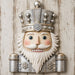 Silver and white winter nutcracker with snowflake details on neutral wood background metal wreath sign