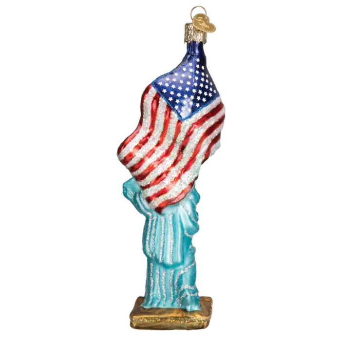 The Statue of Liberty Merck Family Old World Christmas 10181 is a glittery, hand-painted glass ornament with an American flag and gold base—ideal for adding festive, classic charm to your Christmas tree.