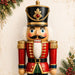 Traditional Christmas nutcracker portrait metal sign featuring a classic red, green, and gold nutcracker with holiday greenery and berries. Exclusive Trendy Tree Design. SKU TTE-532.