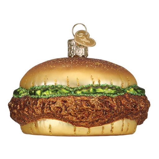 The Chicken Sandwich Old World Christmas Ornament (32567) features a gold bun, green lettuce, and glittery brown patty. It adds quirky charm to your holiday decor with a convenient hanging loop at the top.
