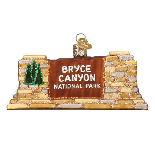 The Bryce Canyon National Park Ornament by Old World Christmas (Product 36304) captures the distinctive charm of the park's entrance sign. It features a brown sign with white text, a green tree emblem, and is surrounded by a stone-like base reminiscent of Utah's famous geological hoodoos.