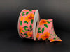 A partially unrolled 1.5X10Y Peach Satin/Orange Magnolias Ribbon (41335-09-23) featuring orange magnolias and green leaves on a dark backdrop beautifully showcases its vibrant floral design.