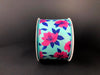 The 2.5X10Y Aqua Satin/Fuchsia Magnolias Ribbon features a floral design with pink flowers and dark blue leaves on an aqua satin background against a dark backdrop.