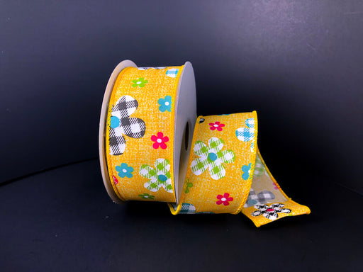The 1.5X10Y Yellow Print Linen/Bf Plaid Flowers Ribbon (41338-09-22) features a wired yellow ribbon with vibrant plaid flowers in red, blue, white, black, and green on a black background, curling gracefully to the right.