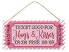 The 12.5L Glitter Ticket Hugs & Kisses Sign (AP7843) in pink/light pink/black/white is a decorative plaque shaped like a glitter ticket, featuring Ticket Good For Hugs & Kisses XO XO FREE XO XO on a striped background with heart accents and an attached rope for easy hanging.