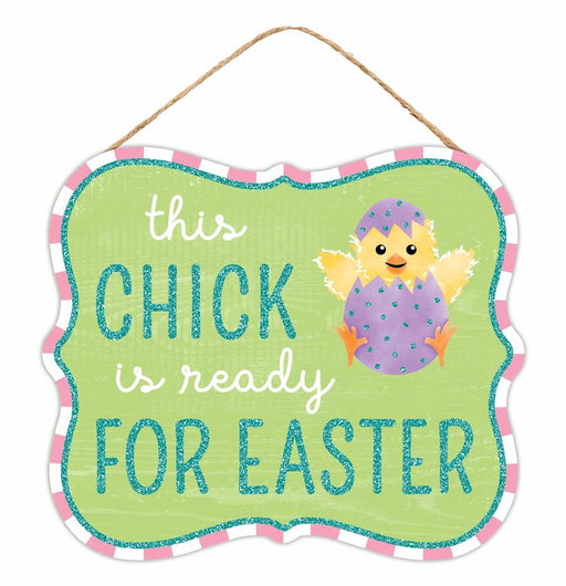 The 10.5L x 9H Easter Glitter Sign features a green MDF background with This chick is ready for Easter in sparkly text. A cute chick emerges from a purple polka-dotted egg, and a pink and white striped border adds charm. Perfect with its hanging rope for festive decor!.