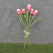 A delightful bunch of 17 red and white tulips with five plastic stems, wrapped delicately with a thin beige string, sits on a gray surface, accented by green grass below.