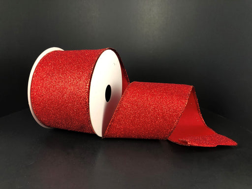 A spool of Red All Flat Glitter wired ribbon, size 2.5x10Y (X820640-12), is unwound against a dark background.