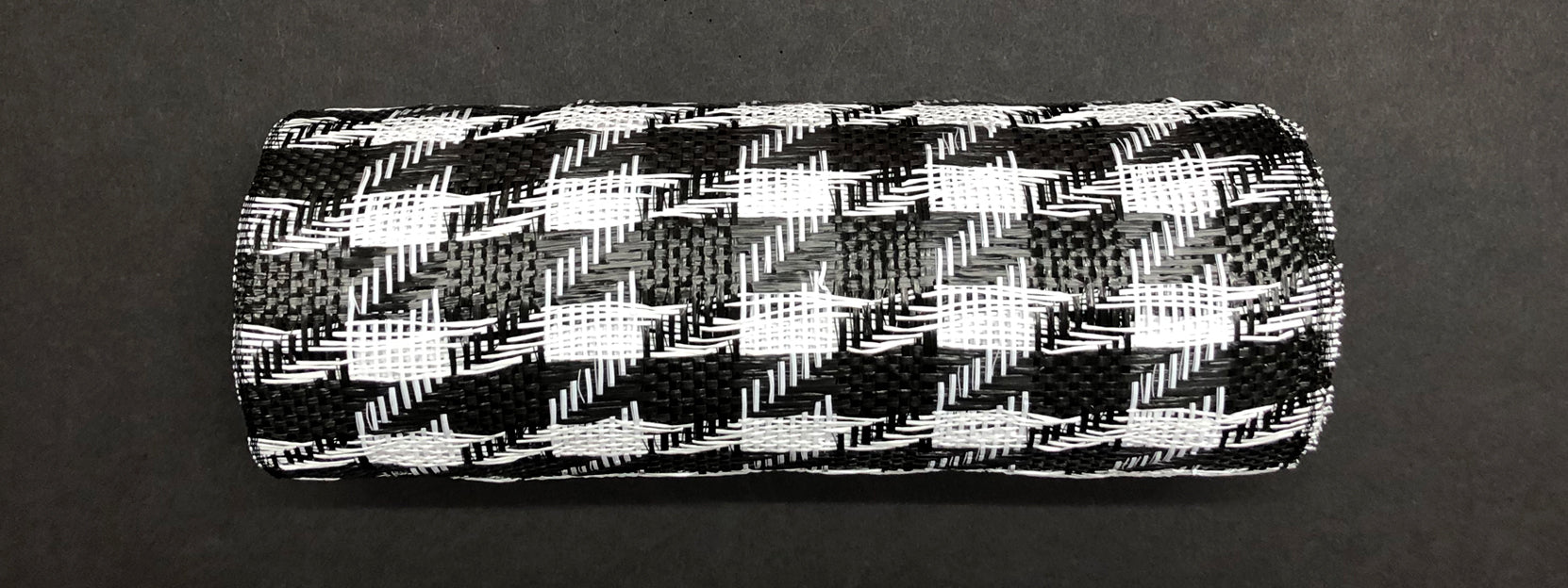 The Houndstooth Black-White Woven Mesh, model XB108910-01, features a bold houndstooth pattern as it lays horizontally on a dark background, highlighting its textured checkered design.